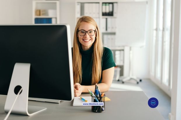 Smiling person wearing blue-light glasses while working on laptop, looking relaxed and productive